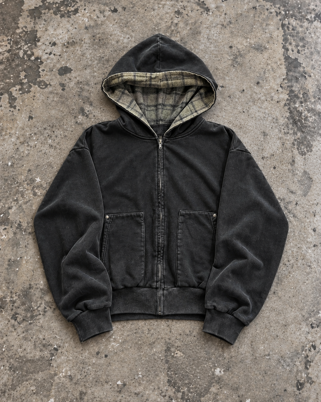 Flannel-lined zip hoodie in washed black, flat lay on concrete