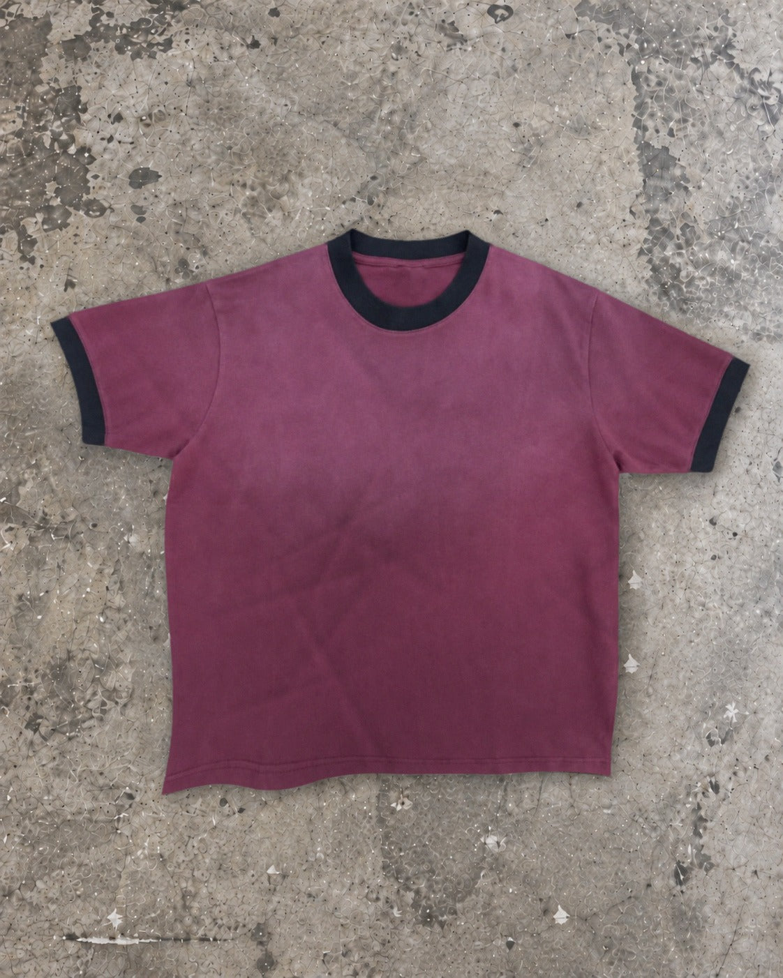 LOS Ringer Tee in Plum with black rib collar and cuffs, laid flat on concrete