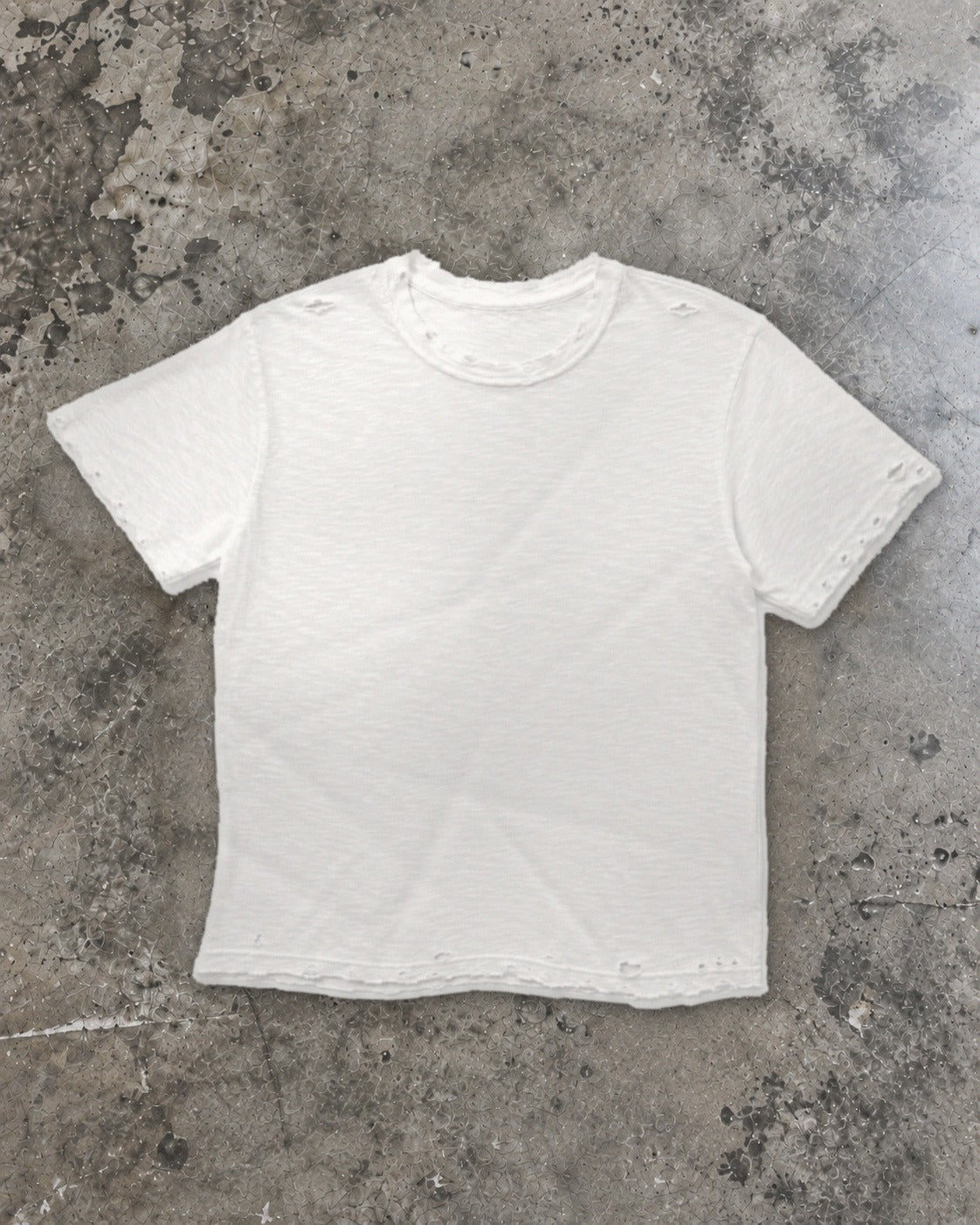 Distressed white slub tee laid flat on concrete