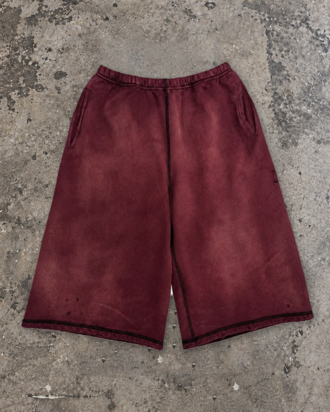 Washed 3/4 capri shorts in burgundy, flat lay on concrete
