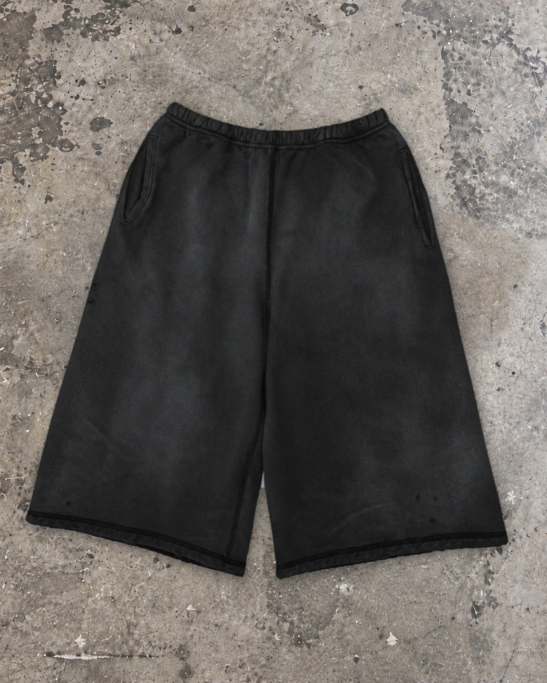 Washed 3/4 capri shorts in washed black, flat lay on concrete